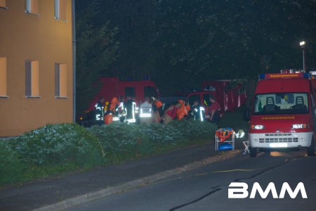 Zu einem mysteriösen Vorfall kam es am Sonntagabend gegen 20.00 Uhr in Neukirch/Lausitz . Aus bislang ungeklärter Ursache sprang ein 52-Jähriger Mieter aus dem vierten Stock eines Mehrfamilienblocks. Alarmierte Rettungskräfte kümmerten sich um den schwerst verletzten Mann und brachten diesen in eine Klinik. Die mit alarmierten Beamten, versuchten sich Zutritt zur Wohnung des Mannes zu verschaffen. Nach mehreren vergeblichen Versuchen, in durch die Wohnungstür Zutritt zur Mieteinheit zu erlangen, entschieden die Beamten vor Ort sich mittels Steckleitern in den vierten Stock zu begeben und durch ein Fenster in die Wohnung zu gelangen. In der Wohnung angekommen, stellten die Beamten eine verbarrikadierte Wohnungstür fest. Ebenso entdeckten sie mehreren Chemikalien und kristallinartige Flüssigkeiten, welche die Alarmglocken der Beamten leuten ließen. Ebenfalls in der Wohnung gefundene Zettel, auf welchen eventuell Nachrichten zum Bau von Bomben oder Sprengvorrichtungen notiert sind wurden ebenfalls entdeckt. Umgehend verliesen die Beamten die Wohnung und alarmierten die Spezialeinheiten des ABC-Zuges des Landkreises Bautzen sowie Spezialisten des LKA. Auch die SEG Wilthen wurde vor Ort alarmiert. Im Einsatzverlauf evakuierten die Einheiten den Mieteingang und begaben sich unter chemischen Schutzanzügen in die Wohnung. Dort entnahmen die Mitglieder der Feuerwehr Proben der unbekannten Stoffen und stellten diese im Anschluss in Zusammenarbeit mit der Polizei sicher. Die Proben sollen in einem Labor untersucht werden. Gegen 5.30 Uhr am Montagmorgen konnten die Bewohner des Einganges wieder in die Wohnung. Verletzt wurde auser dem 52-Jährigen bislang niemand. Auch der Rettungswagen, mit welchem der Patient transportiert wurde, wurde von den Feuerwehrleuten auf chemische oder sonstige gefährliche Stoffe gemessen. Im Rettungswagen ist keine Kntamination durch Gefahrgut festzustellen gewesen.